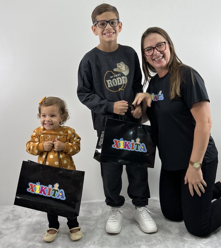 Mamãe e filhos felizes com sacolas de compras Xikita Moda Infantil